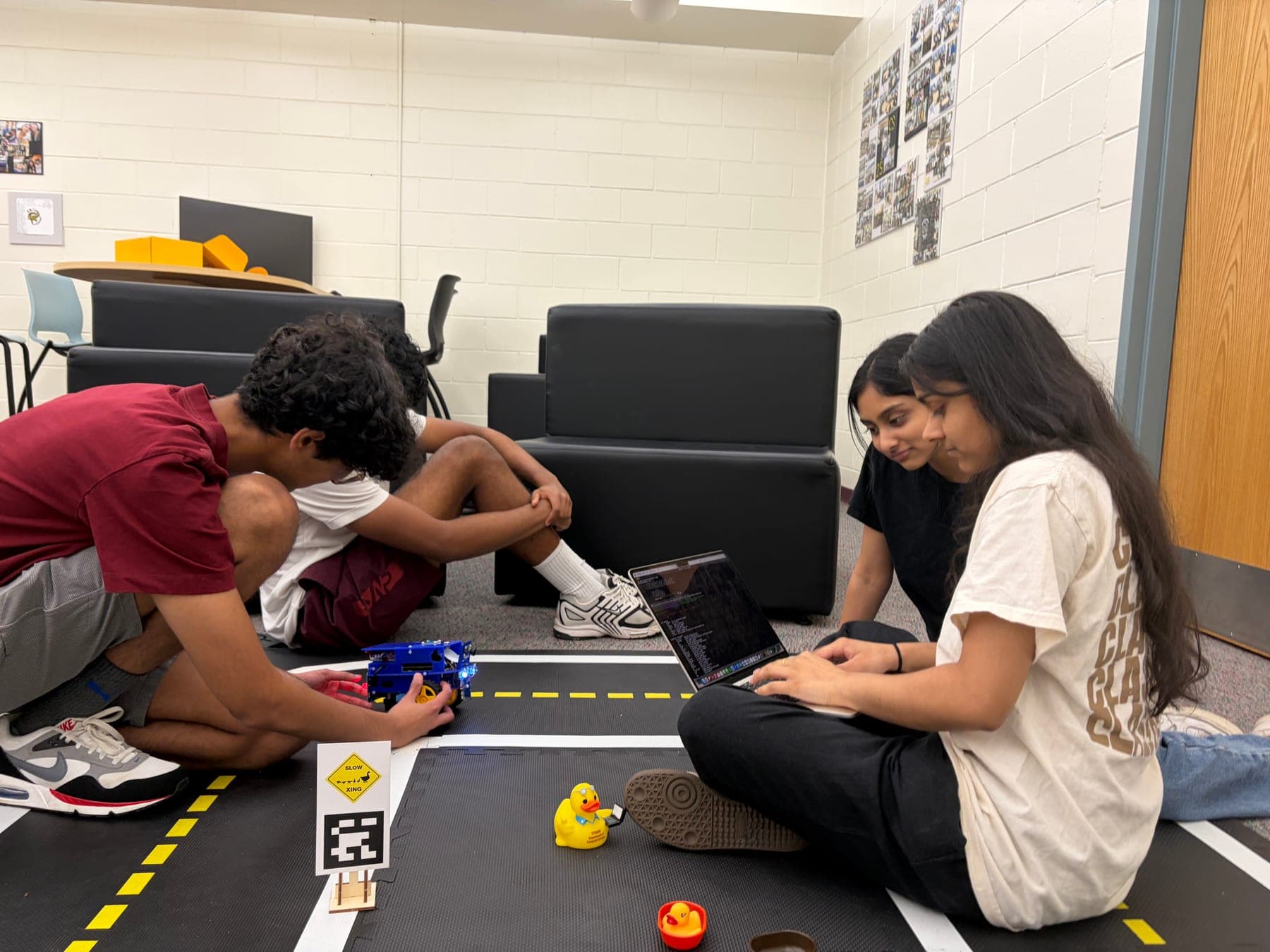 Students debugging a DuckieBot alongside the track