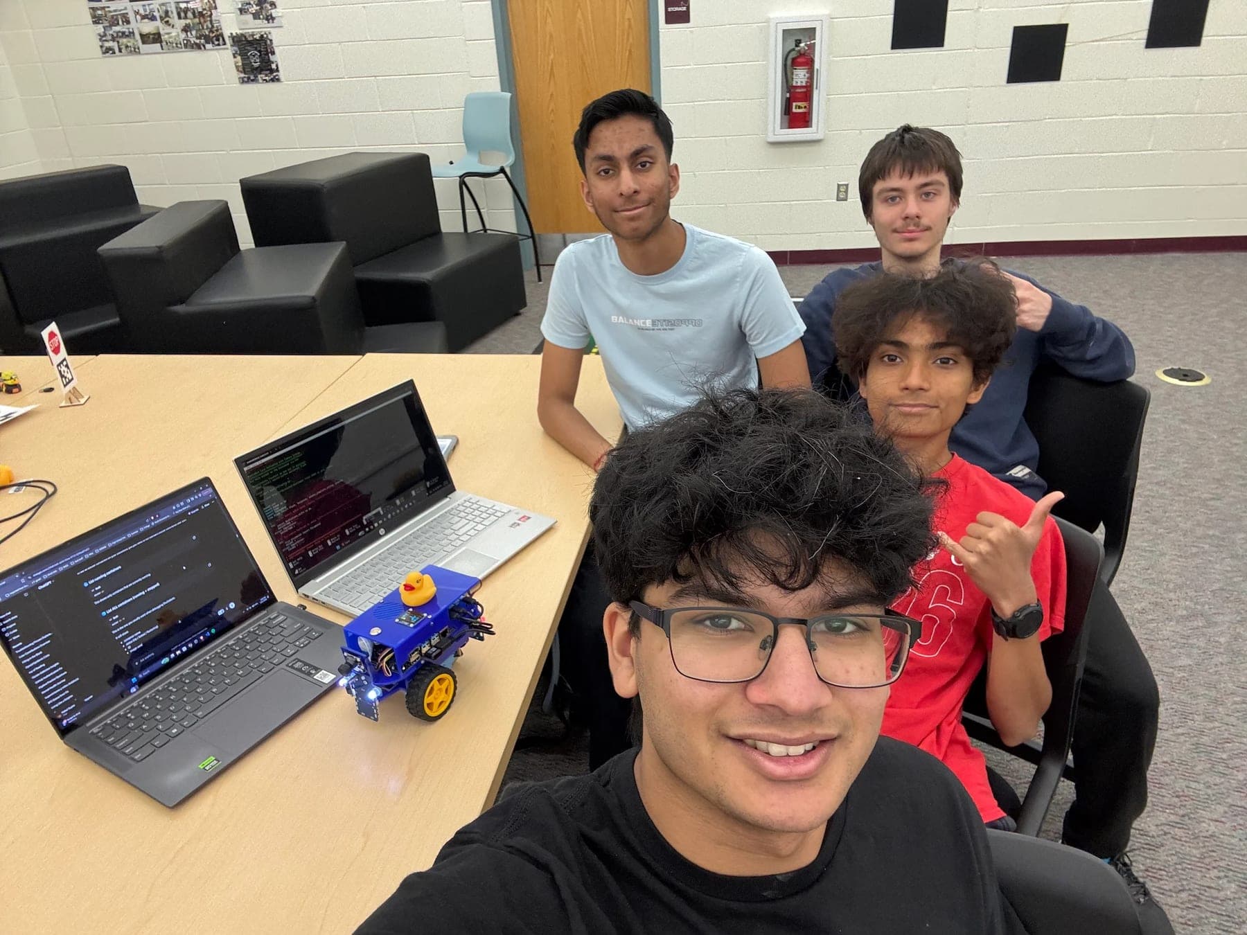 Students with a DuckieBot and their laptops during a build session
